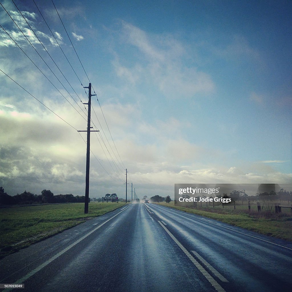 Cars travelling down a straight road after rain