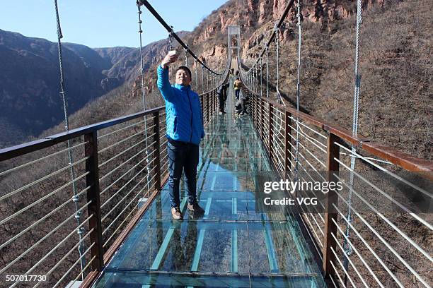 Man takes a selfie on a glass suspension bridge to be completed totally at Fuxishan Tourism Resort on January 26, 2016 in Zhengzhou, Henan Province...