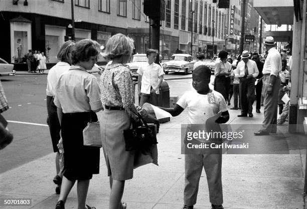 Young NAACP volunteer distributing fliers to passersby announcing upcoming March on Washington for Jobs and Freedom planned for Augist 28, 1963.