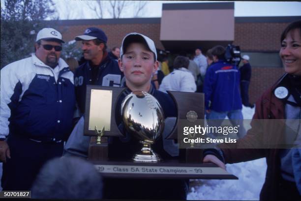 Adam Kechter holding the state football championship trophy given to him by Columbine High School team which adopted him after his older brother team...