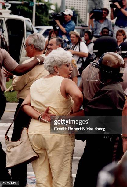 Police arresting woman protesting INS decision to return Elian Gonzalez to Cuba, surviving rafter whose mom drowned when their refugee boat sank, at...