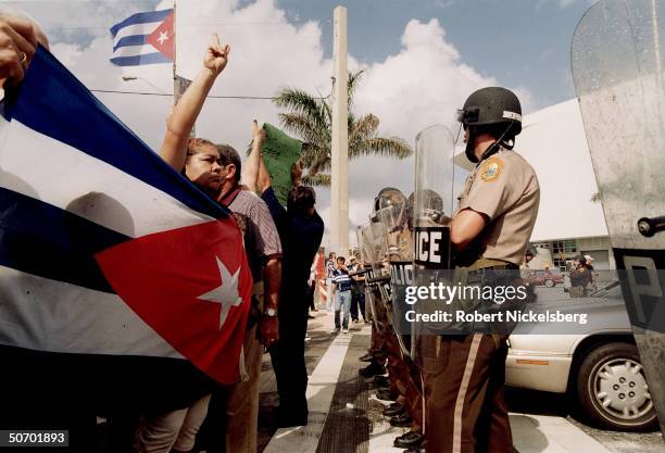Police facing Cuban Americans protesting INS decision to return Elian Gonzalez to Cuba, surviving rafter whose mom drowned when their refugee boat...