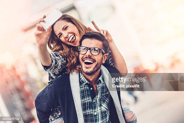 happy couple making selfie outdoors - happy couple using cellphone stockfoto's en -beelden