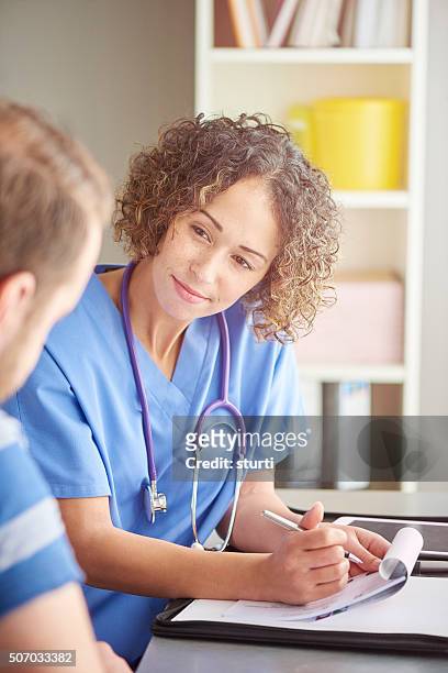 female doctor listening and prescribing. - nurse listening to patient stock pictures, royalty-free photos & images