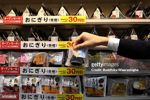An employee arranges Onigiri, rice balls at a newly designed train-shaped convenience store named Lawson + Friends on its opening day at the Itayado...
