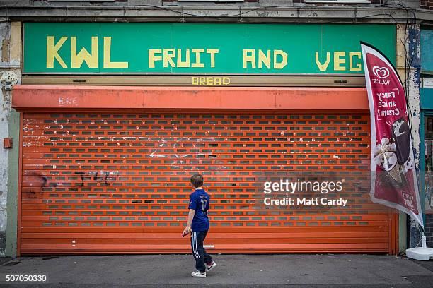 Boy walks past a shop that is closed on a housing estate in Bristol on August 3, 2015 in Bristol, England.