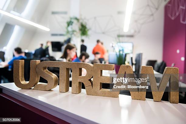 Wooden logo sits on a desk area as employees work at laptop computers beyond, inside the Ustream, Inc. Office in Budapest, Hungary, on Tuesday, Jan....