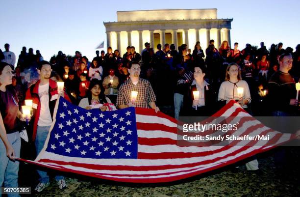 Mourners burning candles and hold the flag during a vigil at the Lincoln memorial to remeber those who died in the terrorist attack on September 11,...