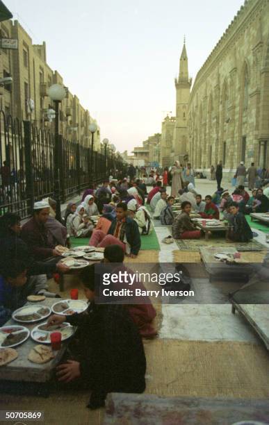 People breaking the fast by eating in the streets and on sidewalks during the month of Ramadan.