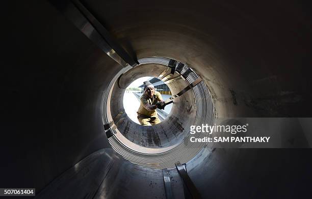An Indian worker unpacks steel coils unloaded from an Indian Railways train at a new private freight terminal in Sachana village near Viramgam, some...