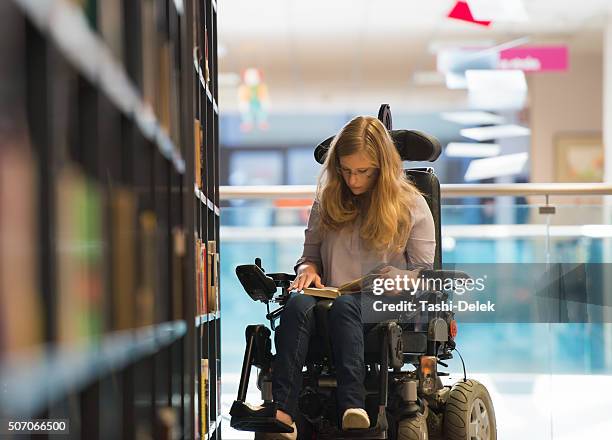 niña en la biblioteca para personas con discapacidades - silla ruedas fotografías e imágenes de stock