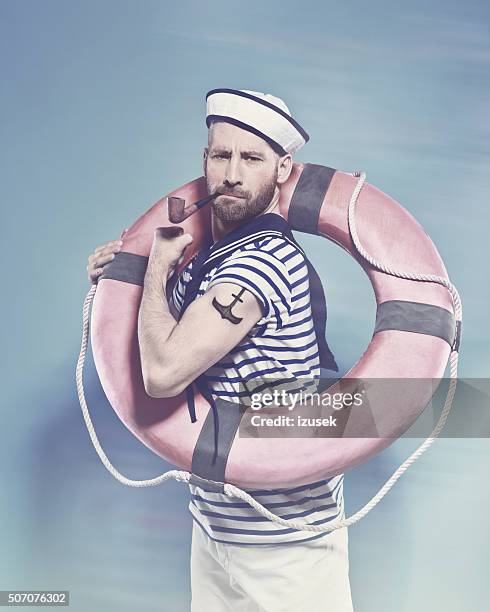 bearded sailor holding lifebuoy and smoking pipe - sailor stock pictures, royalty-free photos & images