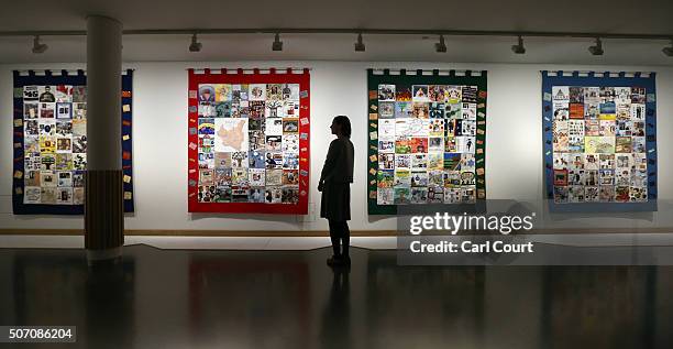 Member of staff poses next to quilts consisting of patches made by some of the orphaned child survivors of the Nazi concentration camps who came to...