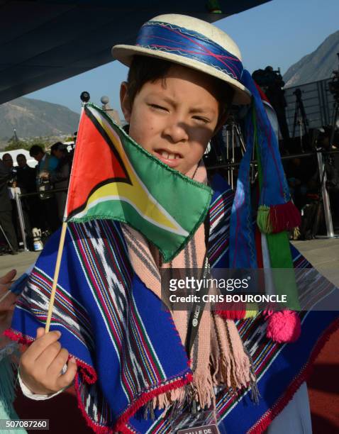An Ecuadorian child in typical attire waves holds Guyana's national flag during the inauguration of the IV Community of Latin American and Caribbean...