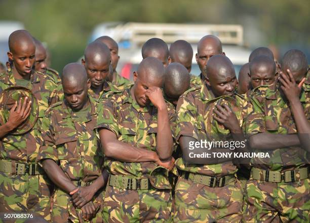 Kenya Defence Forces soldiers bow their heads during prayers for slain comrades at a memorial attended by Kenya's Uhuru Kenyatta, Somalia's Hassan...