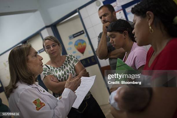 Doctor Angela Rocha, left, talks with the family of Julie Adriana center, while one-month-old son Alexandro Julio is held by his grandmother, right,...
