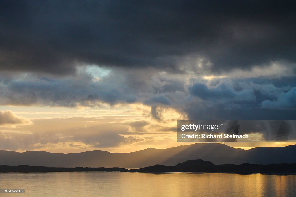 Golden sunset shining on Loch and clouds, over Raasay and Skye, Scotland. Taken from Wester Ross, near Applecross