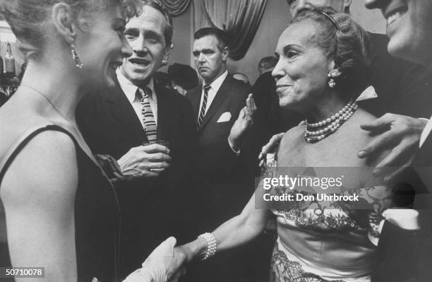 Actress Gwen Verdon and actor Jason Robards talking at a dinner party.