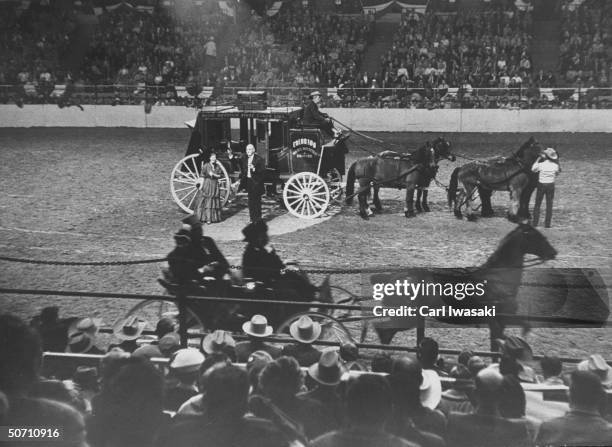 American Beauty Judy Johnston and Pres. Of Natl. Western Stock show L. M. Pexton standing outside of stage coach waving to the crowd.