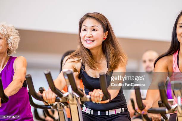 adults taking a exercise class at the gym - spin class stock pictures, royalty-free photos & images