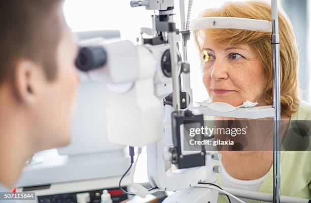 senior woman visiting optician. - eye test 個照片及圖片檔