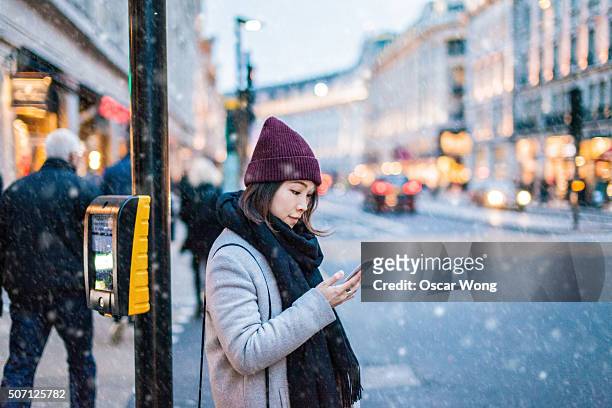 young asian girl using smartphone on the street - london winter stock pictures, royalty-free photos & images