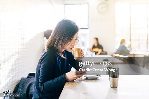 Young Asian girl using mobile phone in cafe Young Asian girl using mobile phone in cafe