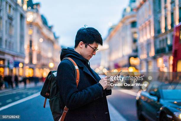 young man using mobile phone on the street - menschen vor laden stock-fotos und bilder