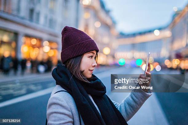 young asian lady taking picture on the high street - flagship store stock pictures, royalty-free photos & images