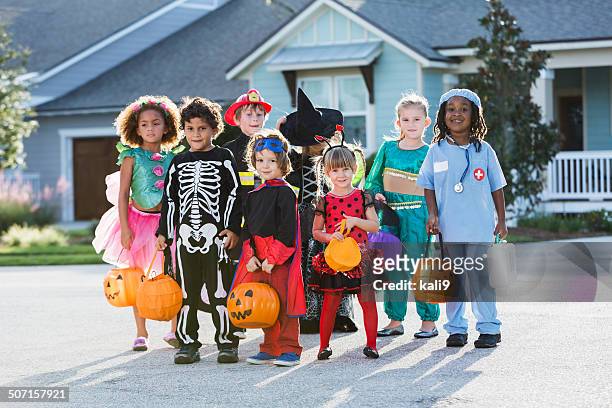 group of children in halloween costumes in front of house - stage costume stock pictures, royalty-free photos & images
