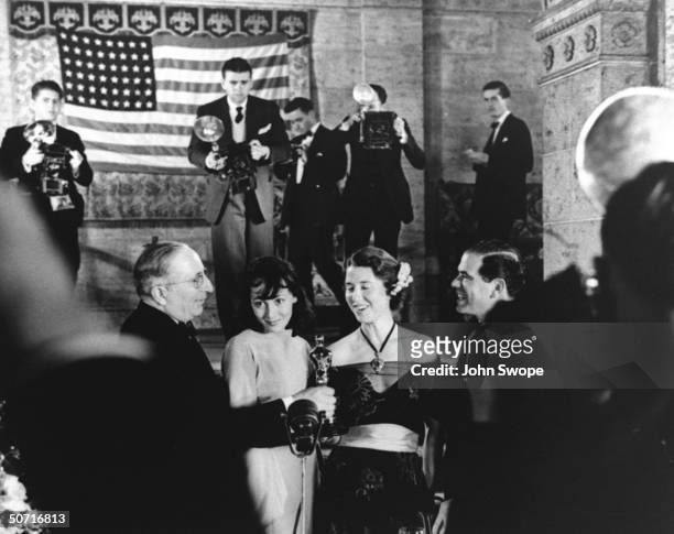 Studio chief Louis B. Mayer, actress Luise Rainer, unidentified and director Frank Capra during Academy Awards presentation , as photographers work...
