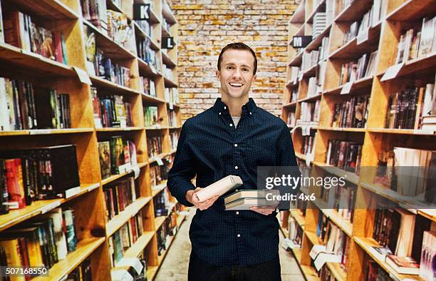 smiling male bookseller in library - librarian stock pictures, royalty-free photos & images