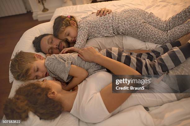 junge familie, die zusammen ein nickerchen auf einem bett. - family on bed stock-fotos und bilder