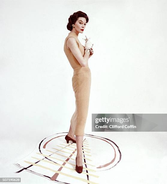 Model wearing golden beige dress in lamb's wool and angora by Tina Leser, with sepia red stacked heel pumps by Confettis.