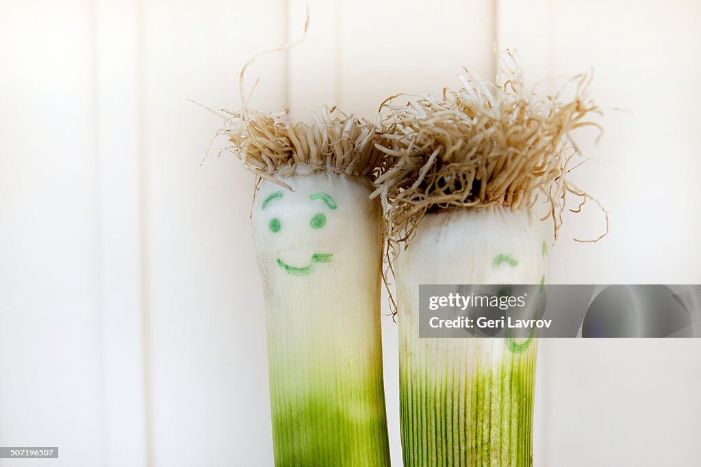 Two green onions with smiley faces drawn on them