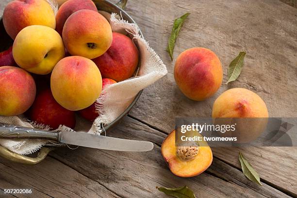 peaches on moody rustic wooden kitchen table top background. - pfirsichkern stock-fotos und bilder