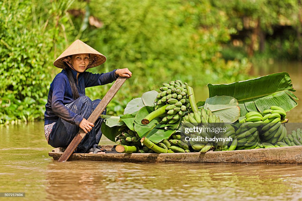 Vietnamese woman rowing  boat in the Mekong River Delta, Vietnam