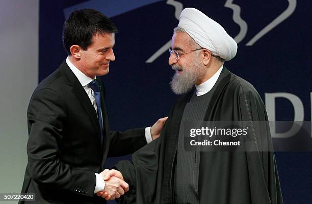 French Prime Minister Manuel Valls shakes hands with Iranian President Hassan Rouhani after a meeting at the French employers association MEDEF...