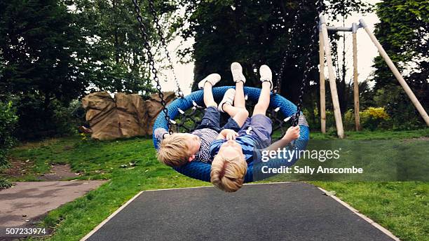 Two little boys playing on a swing