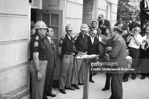 Governor George Wallace attempting to block integration at the University of Alabama stands in the door of Foster Auditorium while being confronted...