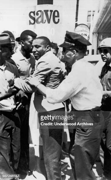Policeman applies an arm lock on comedian Dick Gregory after he left the Leflore County Court House to help Negroes register to vote, Greenwood,...