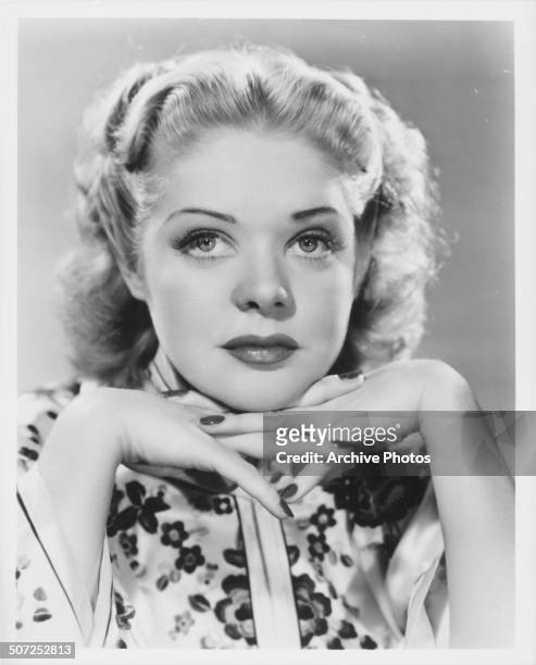 Promotional headshot of actress Alice Faye, resting her chin on her hands, circa 1935.