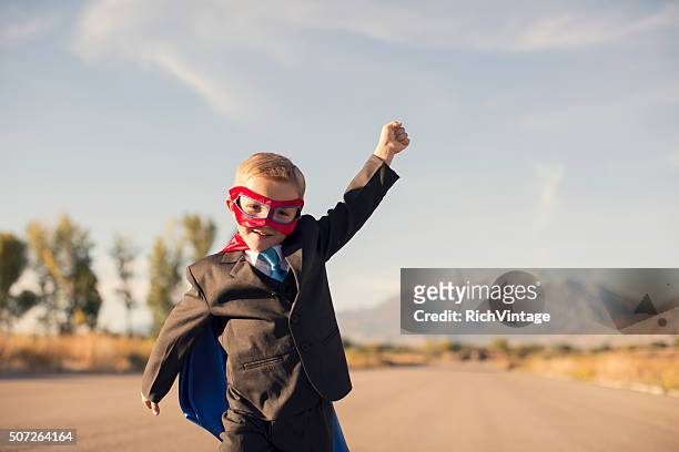 young boy in superhero costume and business suit is running - growth mindset stock pictures, royalty-free photos & images