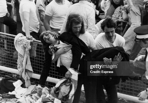 An unconscious teenage girl is carried away following a crowd incident, where a crash barrier collapsed at a David Cassidy concert, White City,...