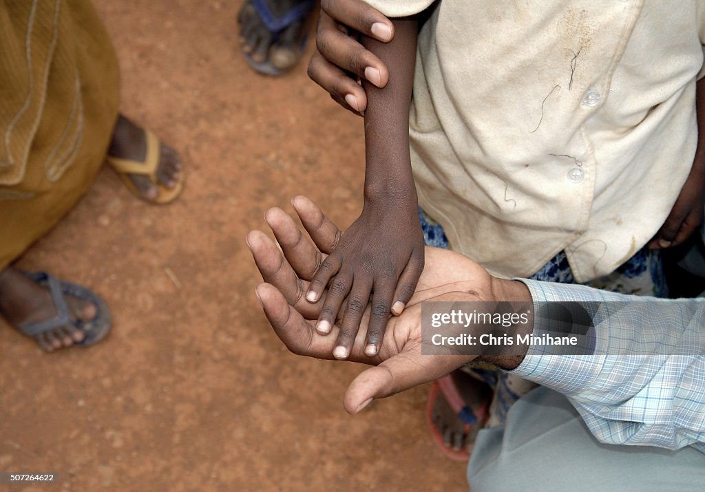 Thin starving child's hand in adult's hand.