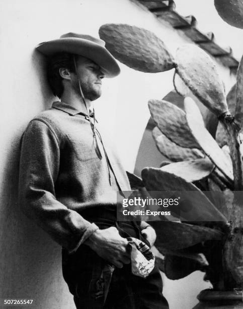 Actor Clint Eastwood in cowboy costume, leaning against the wall of his hotel in Rome, circa 1960.