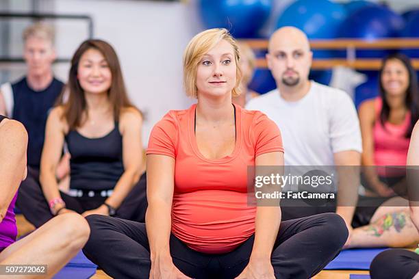 pregant woman taking a yoga class - pregnancy class stockfoto's en -beelden