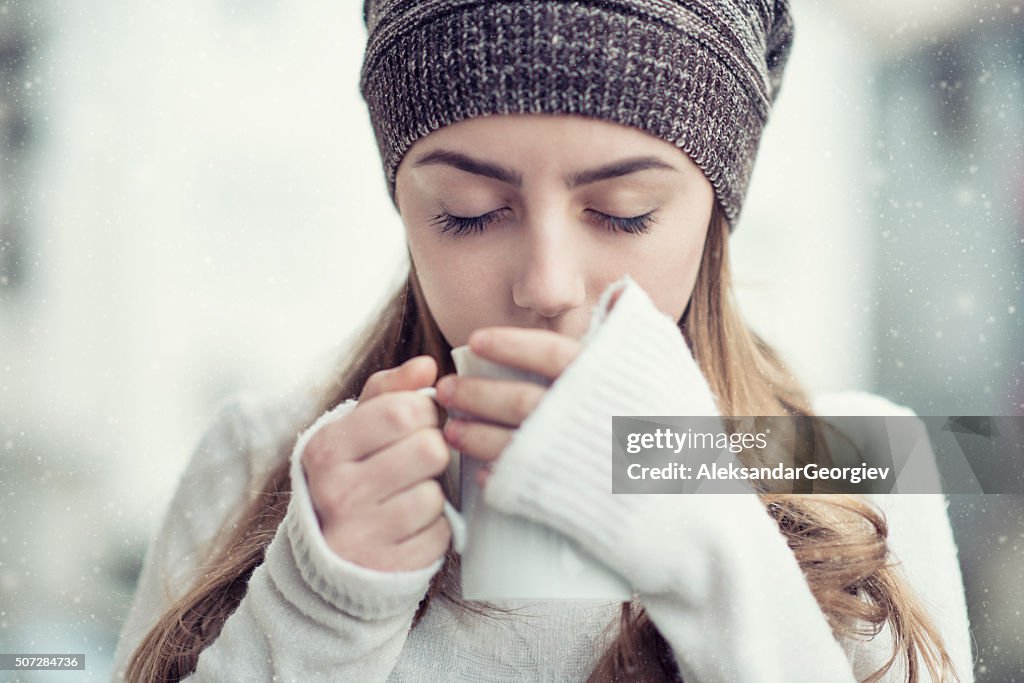 Rapariga loura fofinho a beber chá quente durante o inverno neve