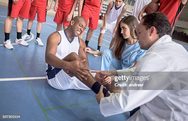 doctor checking an ankle injury at a basketball game - sports medicine stockfoto's en -beelden