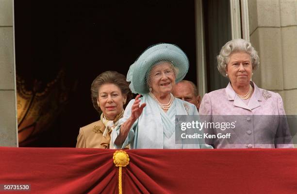 Britain's Queen Mother in blue dress and hat flanked by her daughters Princess Margaret and Queen Elizabeth II in lavender dress celebrating the...